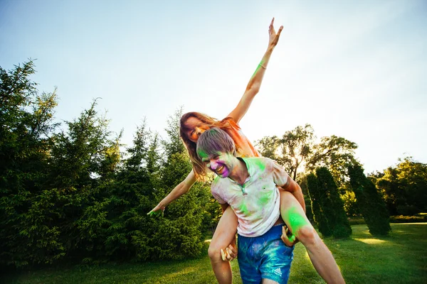 Jovem e belo casal brincando no parque em holi cor fes — Fotografia de Stock