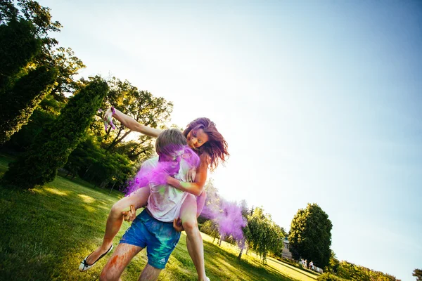 Jovem e belo casal brincando no parque em holi cor fes — Fotografia de Stock