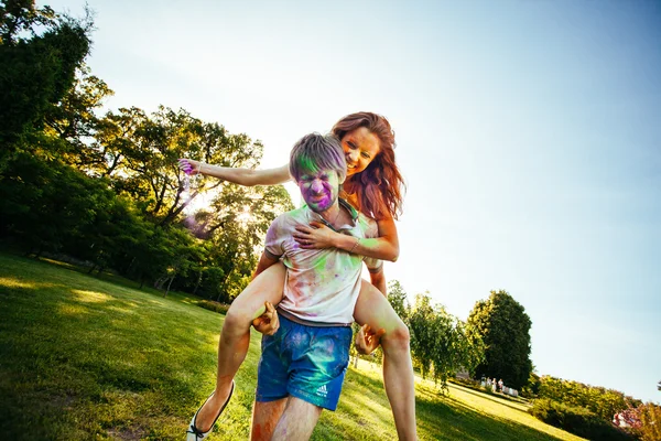 Jovem e belo casal brincando no parque em holi cor fes — Fotografia de Stock