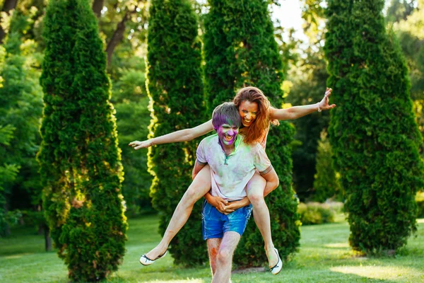 Jovem e belo casal brincando no parque em holi cor fes — Fotografia de Stock