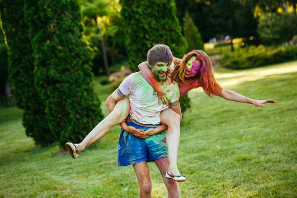 Jovem e belo casal brincando no parque em holi cor fes — Fotografia de Stock