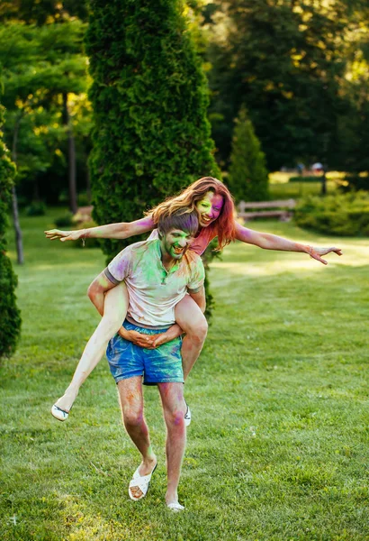 Jovem e belo casal brincando no parque em holi cor fes — Fotografia de Stock