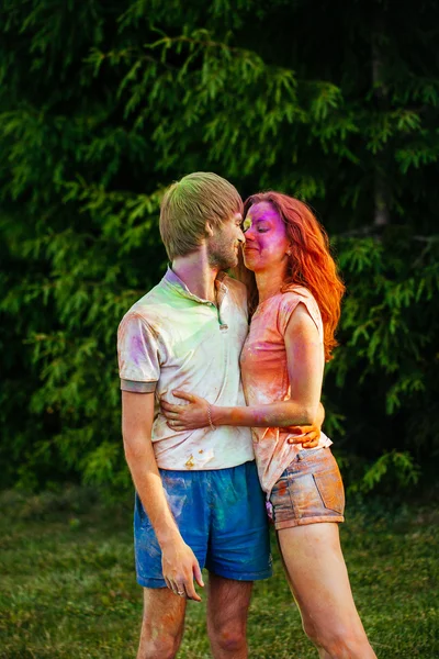 Retrato de um belo jovem casal em um parque na cor holi fes — Fotografia de Stock