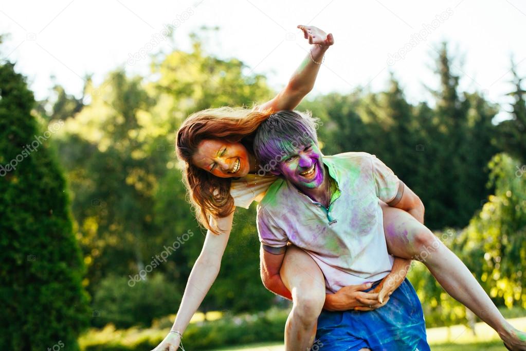 Young and beautiful couple playing in the park on holi color fes