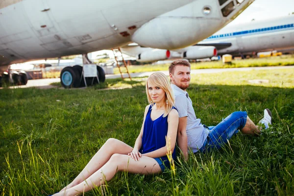 Elegante casal de pé perto de um avião no aeroporto. lua-de-mel — Fotografia de Stock