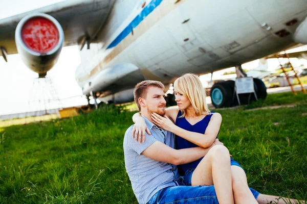 Snygg par står nära ett plan på flygplatsen. smekmånad — Stockfoto