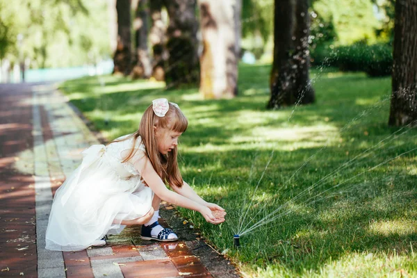 Ragazzina felice che gioca con uno spruzzo d'acqua nel parco — Foto Stock