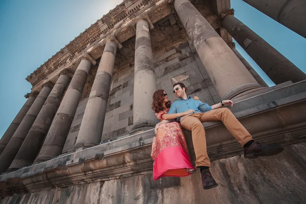 Young couple sitting near the ancient temple of Garni in Armenia — Stock Photo, Image