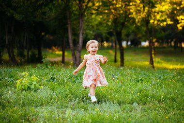 Parkta çim üzerinde çalışan mutlu sevimli küçük kız. Happine