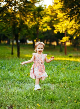 Parkta çim üzerinde çalışan mutlu sevimli küçük kız. Happine