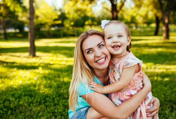 Feliz mamá y su hija sonriendo a la naturaleza. — Foto de Stock