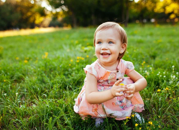 Kleines Mädchen sitzt auf dem Gras. — Stockfoto