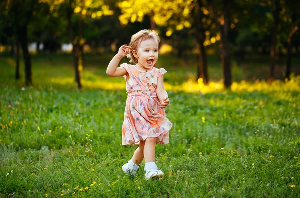 Joyeux petite fille mignonne courant sur l'herbe dans le parc. Ça arrive. — Photo