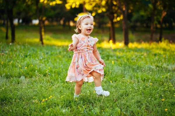 Feliz niña linda corriendo sobre el césped en el parque. Happine. —  Fotos de Stock