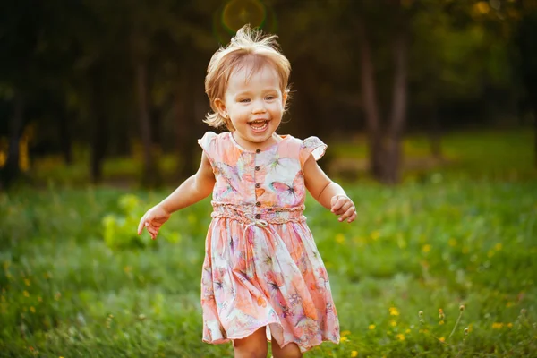 Glad söt liten flicka kör på gräset i parken. Happine — Stockfoto