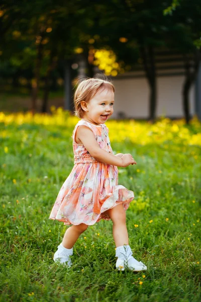 Feliz niña linda corriendo sobre el césped en el parque. Happine. —  Fotos de Stock