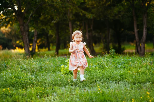 Feliz niña linda corriendo sobre el césped en el parque. Happine. —  Fotos de Stock