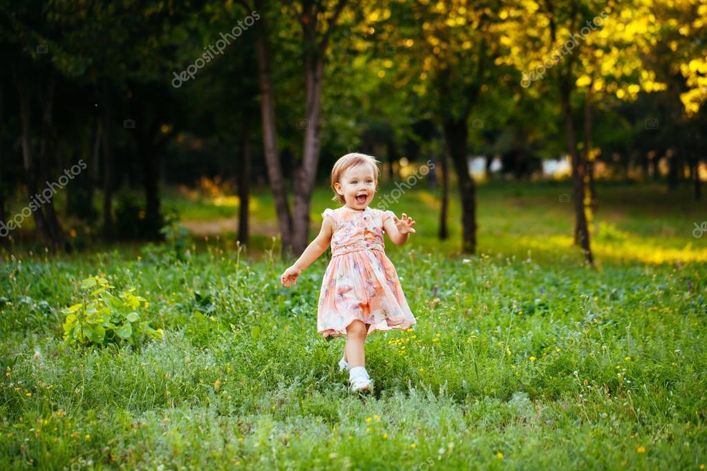 Happy cute little girl running on the grass in the park. Happine