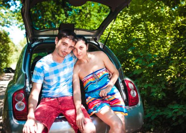 Genç gezginler bir arabanın bagajında otururken haritaya bakıyordum