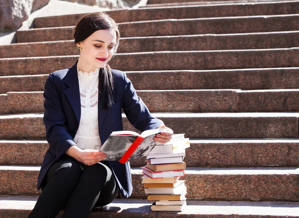 Güzel kız öğrenci merdivenlerde oturan ve bir kitap okuma — Stok fotoğraf