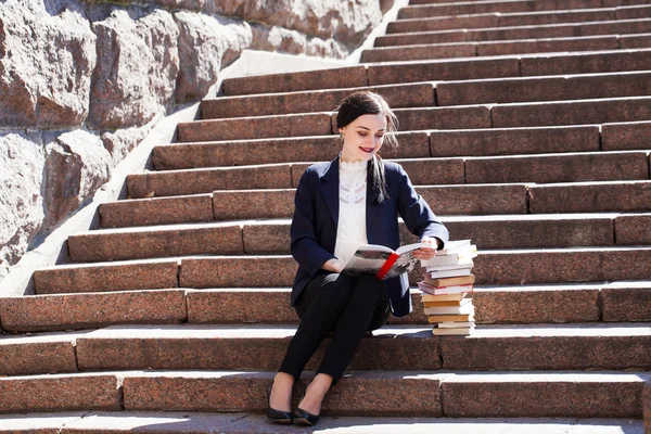 Όμορφο κορίτσι φοιτητής κάθεται σε σκαλοπάτια και διαβάζοντας ένα βιβλίο — Φωτογραφία Αρχείου