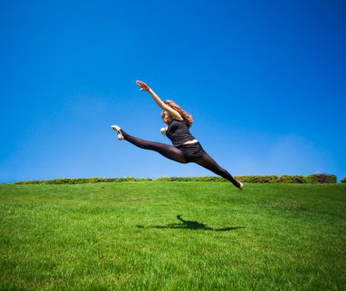 Gülümseyen genç jimnastikçi bölmedeki atlama ve yukarıda yüzen