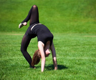 Güneşli günde çimenlerin üzerinde genç jimnastikçi