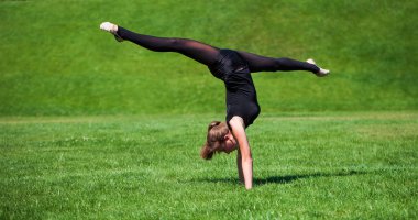 Güneşli günde çimenlerin üzerinde genç jimnastikçi