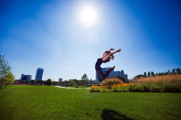 Leende unga gymnasten hoppning i split och svävar ovanför den — Stockfoto