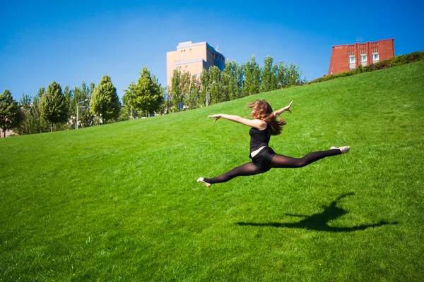 Leende unga gymnasten hoppning i split och svävar ovanför den — Stockfoto