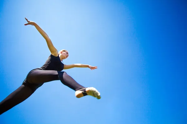 Leende unga gymnasten hoppning i split och svävar ovanför den — Stockfoto