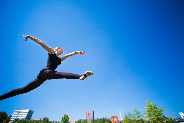 Souriant jeune gymnaste saute en fente et flottant au-dessus de la — Photo