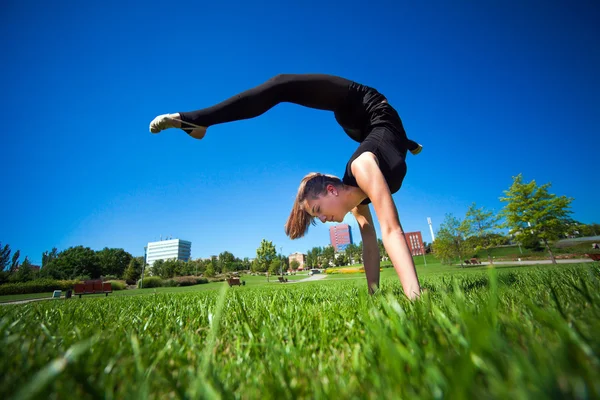 Unga gymnasten på gräset i solig dag — Stockfoto