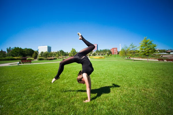 Unga gymnasten på gräset i solig dag — Stockfoto