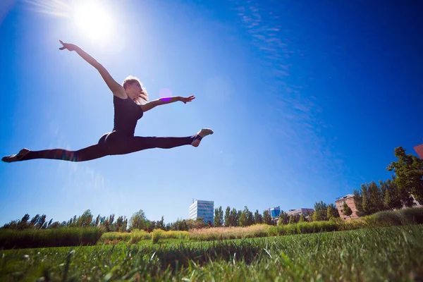 Leende unga gymnasten hoppning i split och svävar ovanför den — Stockfoto