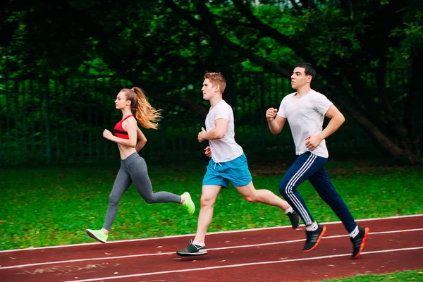 Jóvenes corriendo en pista de estadio — Foto de Stock