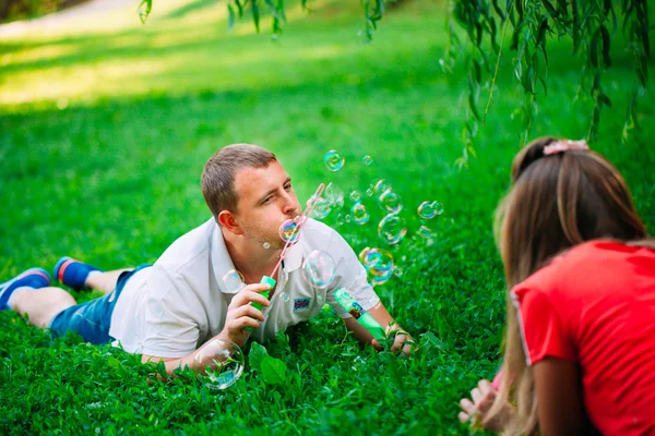 Casal Relaxante no Parque com soprador de bolhas. Hora da Primavera — Fotografia de Stock