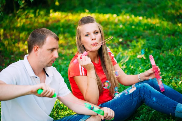 Casal Relaxante no Parque com soprador de bolhas. Hora da Primavera — Fotografia de Stock