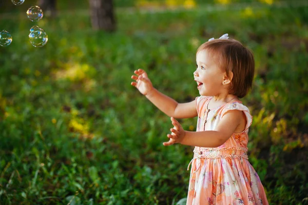 Une jolie petite fille jouant avec des bulles de savon dans le parc . — Photo