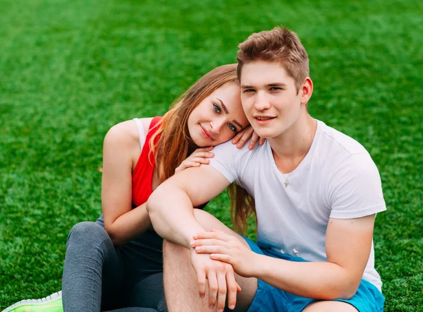 Jeune couple athlétique assis sur l'herbe — Photo