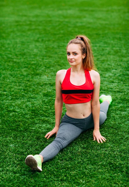 Giovane ragazza fitness seduta su erba verde  . — Foto Stock
