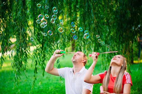 Casal Relaxante no Parque com soprador de bolhas. Hora da Primavera — Fotografia de Stock