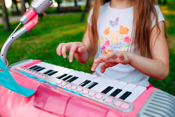 Маленькая девочка играет на игрушечном пианино в парке — стоковое фото