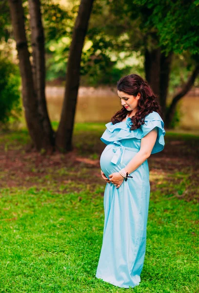 Piękna kobieta w ciąży relaksujący poza w parku — Zdjęcie stockowe