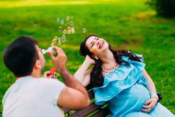 Schönes schwangere Paar entspannt sich draußen im Park. — Stockfoto