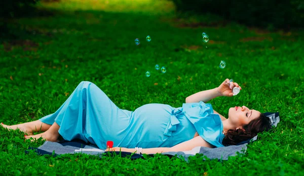 Beautiful pregnant woman relaxing outside in the park Stock Picture