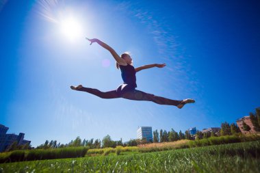 Gülümseyen genç jimnastikçi bölmedeki atlama ve yukarıda yüzen