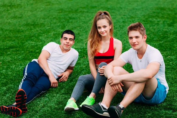 Jeunes sportifs assis sur l'herbe — Photo