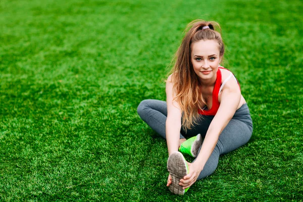 Dziewczynka fitness młody siedzi na zielonej trawie . — Zdjęcie stockowe