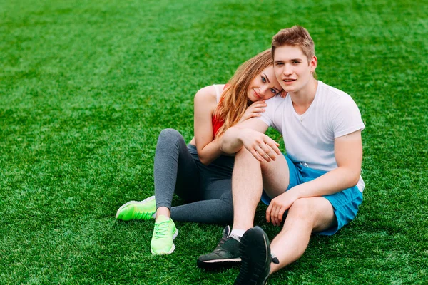 Jeune couple athlétique assis sur l'herbe — Photo